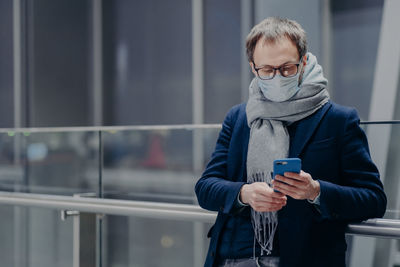 Man using smart phone while standing by railing