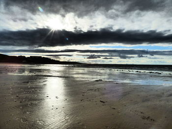 Scenic view of beach against cloudy sky