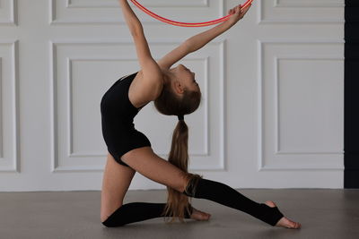 Little sports girl doing exercises with a hula hoop