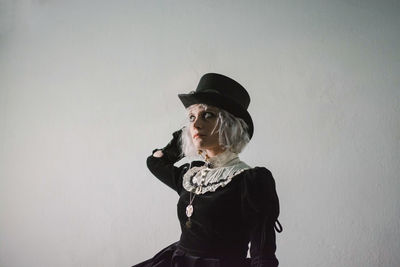 Thoughtful woman wearing costume while sitting against wall at home