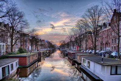 Canal amidst buildings against sky during sunset