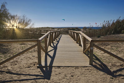 Wooden railing on beach against clear sky