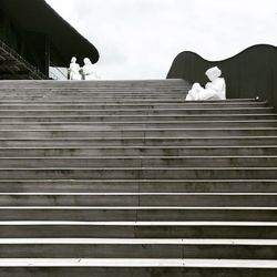 Low angle view of people sitting on staircase against sky