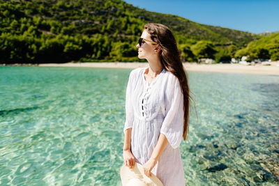 Side view of young woman standing against lake