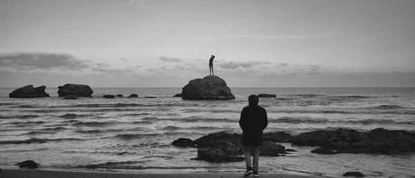 Rear view of young woman looking at sea against sky