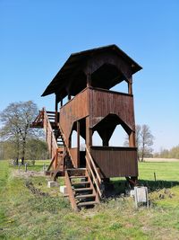 Built structure on field against clear blue sky