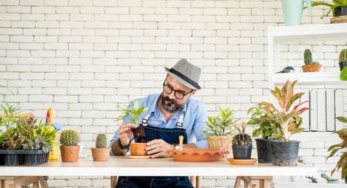 Man and woman using smart phone by potted plant on table