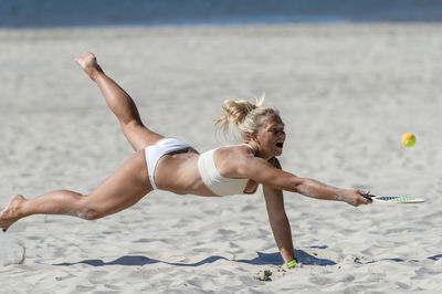 Full length of woman playing tennis on beach