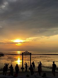 Silhouette people playing on beach against sky during sunset