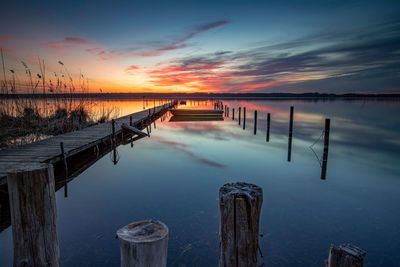 Pier over lake against sky during sunset