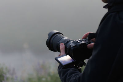 Photographer shooting misty outdoor scene with modern digital camera on a tripod with flip screen