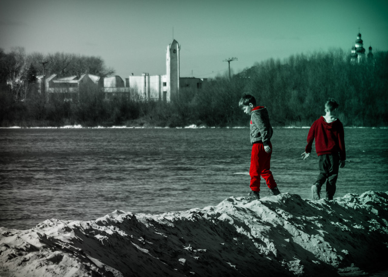 PEOPLE STANDING ON SNOW COVERED SHORE