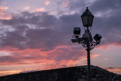 Low angle view of lamp post against cloudy sky during sunset