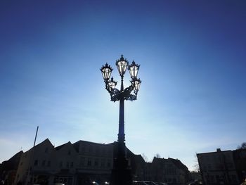 Low angle view of lamp post in city against sky