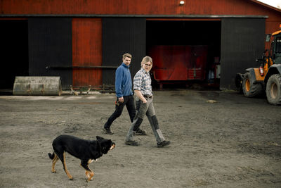 Farmers with dog walking together outside factory