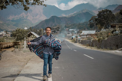 Portrait of woman standing on road against mountain range