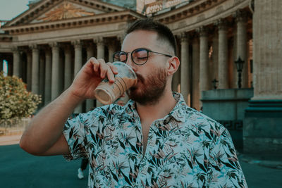 Portrait of young man drinking glass outdoors