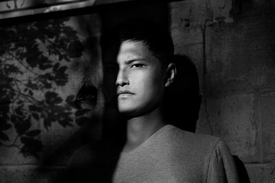Portrait of young man looking away against wall