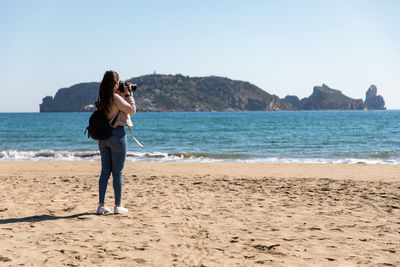 Full length of woman standing at beach against sky