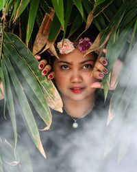 Close-up portrait of young woman standing against tree