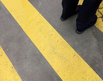 Low section of man standing by yellow markings on road