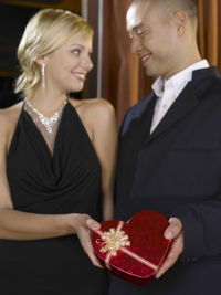 Young couple holding gift box while standing in room