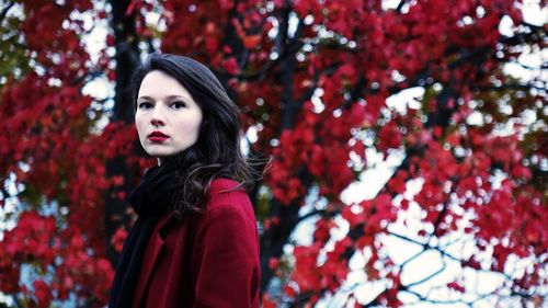 Portrait of woman standing by red flowering tree