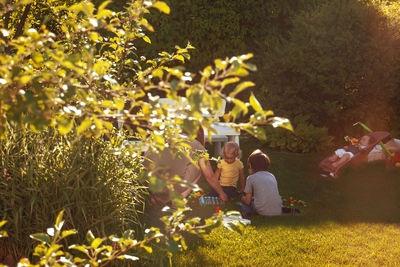 Family sitting on grass in park against trees