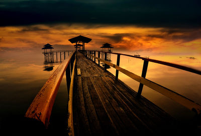 Pier over sea against sky during sunset