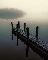 Pier on lake against sky during sunset