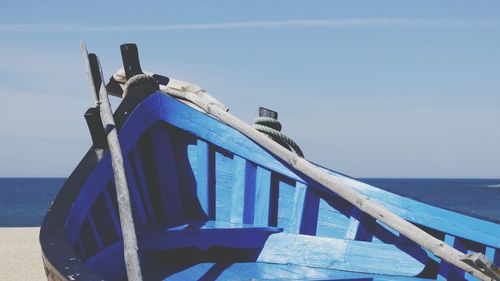 Close-up of deck chairs on beach against clear blue sky