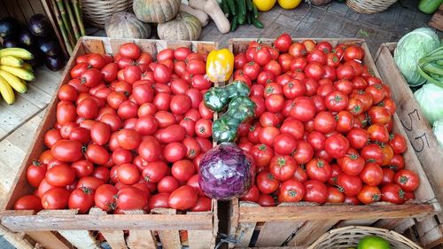 High angle view of red fresh tomatoes in wooden crates for sale at market stall