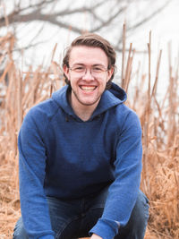 Portrait of smiling young man sitting on field