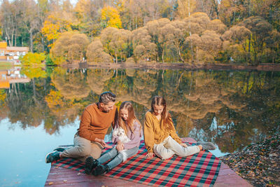 Woman sitting by lake during autumn