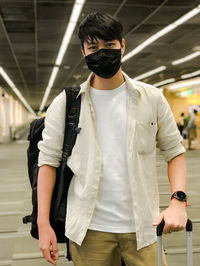 Portrait of young man wearing mask standing at airport