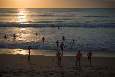 People at beach during sunset