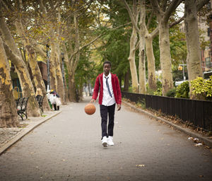 Thoughtful student with basketball listening music while walking