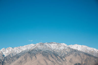 Low angle view of snowcapped mountain against clear blue sky