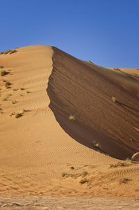 Sand dune in desert against clear sky