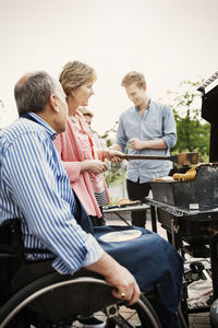 Grandparents with brothers barbecuing at yard