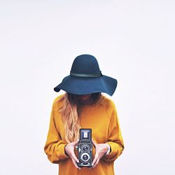 Woman holding camera against white background