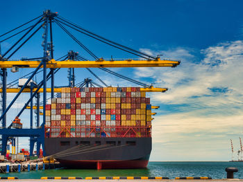 Cranes at commercial dock against sky