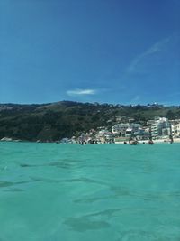 Scenic view of sea and buildings against blue sky