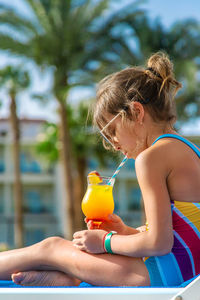 Side view of young woman drinking water in park