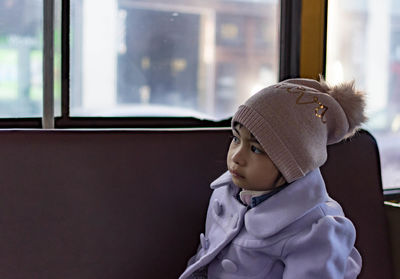 Cute girl sitting in bus while looking away