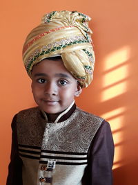 Portrait of boy in traditional clothing and turban against wall