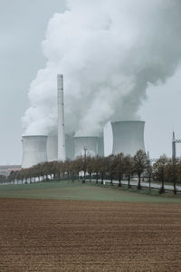 Smoke emitting from factory against sky