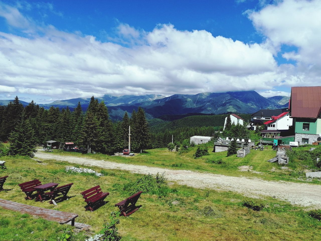 sky, mountain range, mountain, architecture, plant, cloud, landscape, built structure, grass, environment, nature, building exterior, building, scenics - nature, house, rural area, beauty in nature, tree, no people, land, meadow, day, residential district, green, travel destinations, tranquility, field, outdoors, rural scene, tranquil scene, non-urban scene, farm, village, travel, plain