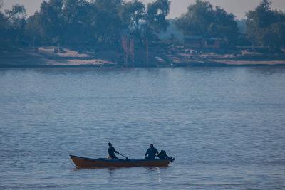 People in boat on lake against sky