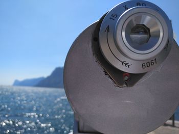 Close-up of camera against sky and lake 